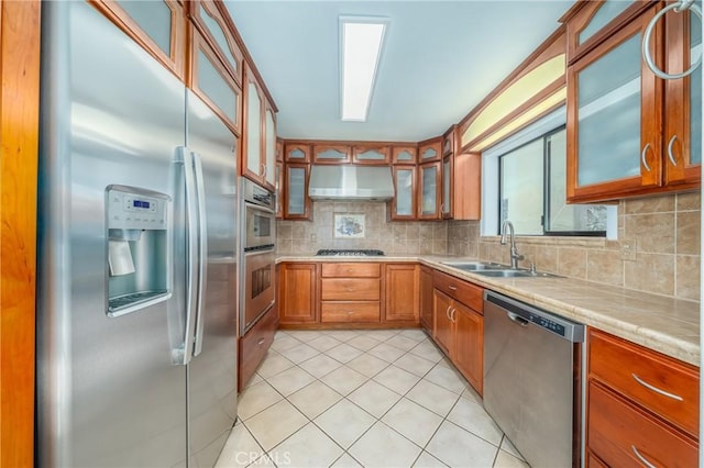 kitchen with glass insert cabinets, under cabinet range hood, tasteful backsplash, a sink, and stainless steel appliances
