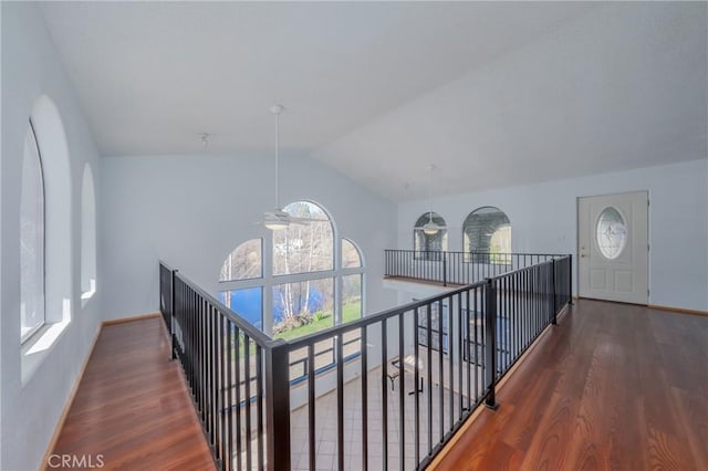 hall featuring plenty of natural light, wood finished floors, vaulted ceiling, and an upstairs landing
