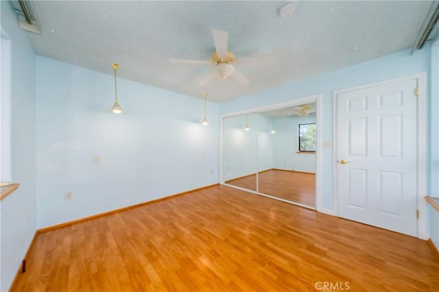 unfurnished bedroom featuring light wood-style floors, baseboards, a ceiling fan, and a closet