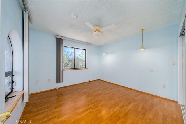 spare room with baseboards, ceiling fan, and light wood-style flooring