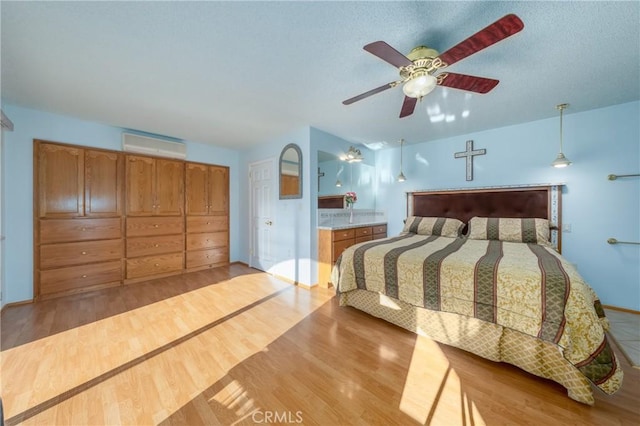 bedroom featuring a wall mounted AC, ceiling fan, and light hardwood / wood-style flooring