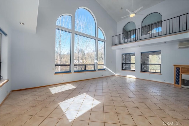 unfurnished living room with an AC wall unit, plenty of natural light, light tile patterned floors, and high vaulted ceiling