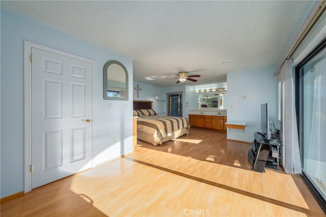 bedroom with baseboards, a textured ceiling, wood finished floors, and connected bathroom
