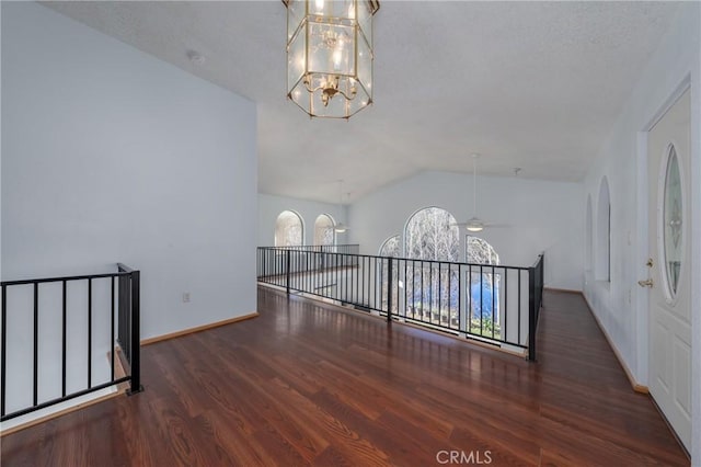 interior space featuring baseboards, an inviting chandelier, wood finished floors, and vaulted ceiling
