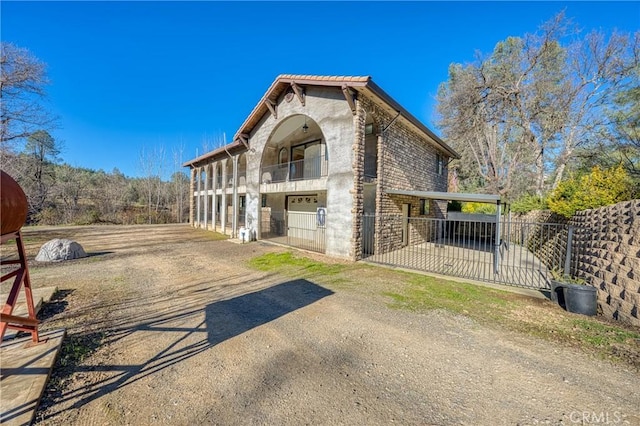 view of front facade featuring a garage, fence, driveway, and a balcony