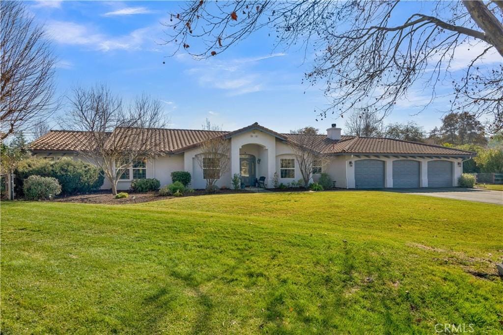 mediterranean / spanish-style home featuring a garage and a front lawn