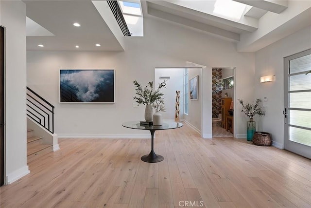 foyer entrance featuring a skylight and light hardwood / wood-style flooring