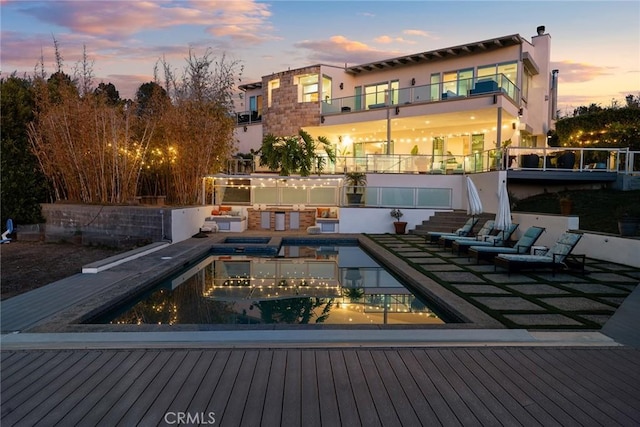 pool at dusk with area for grilling and a patio area