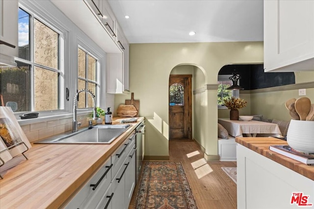 kitchen featuring sink, white cabinetry, wooden counters, dark hardwood / wood-style flooring, and decorative backsplash