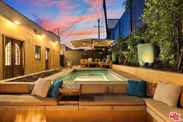 pool at dusk featuring an outdoor living space, an in ground hot tub, a patio, and french doors