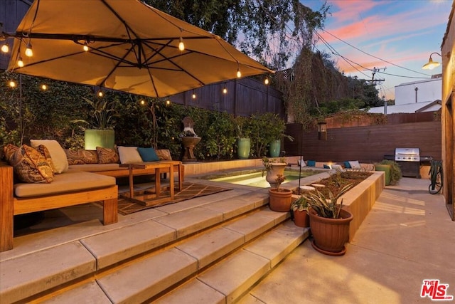 patio terrace at dusk featuring area for grilling and an outdoor living space