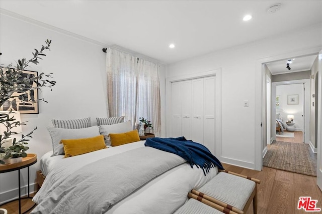 bedroom with crown molding, wood-type flooring, and a closet