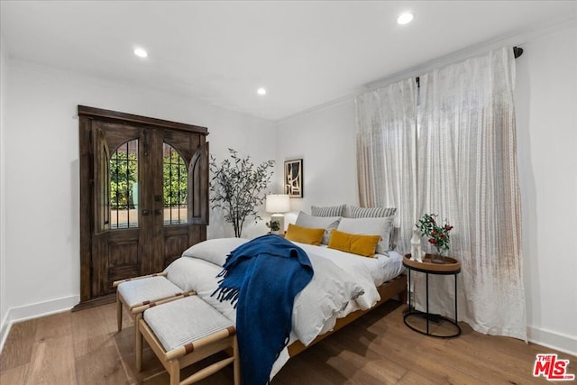 bedroom featuring access to exterior, crown molding, wood-type flooring, and french doors