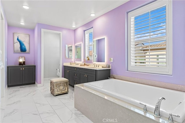 bathroom with vanity, toilet, and a tub