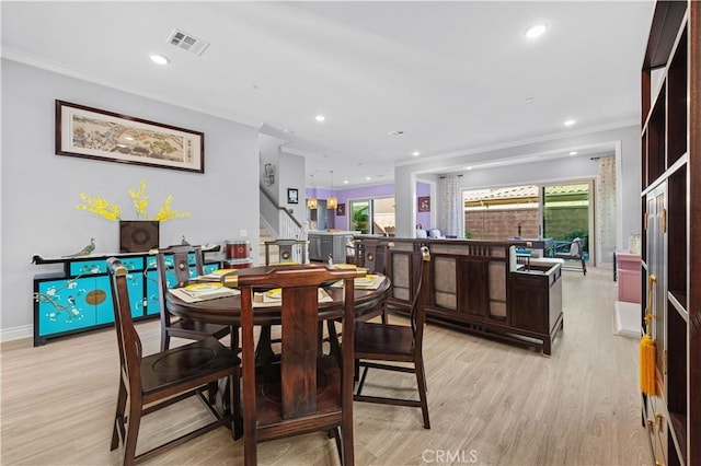 dining space with ornamental molding and light wood-type flooring