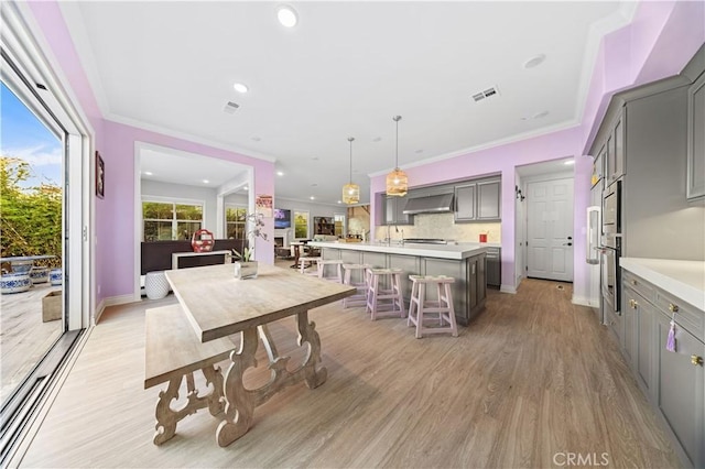 dining room with ornamental molding and light wood-type flooring