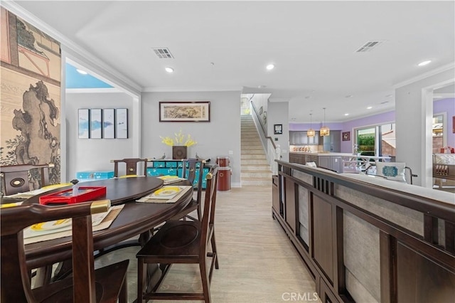 dining area with crown molding and light hardwood / wood-style floors