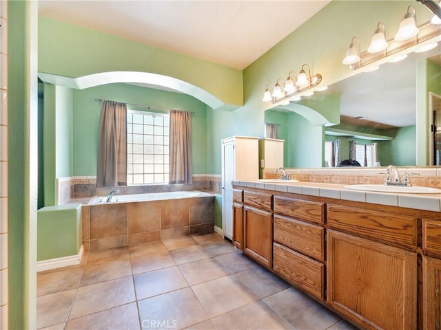 bathroom featuring tiled tub, vanity, and tile patterned floors