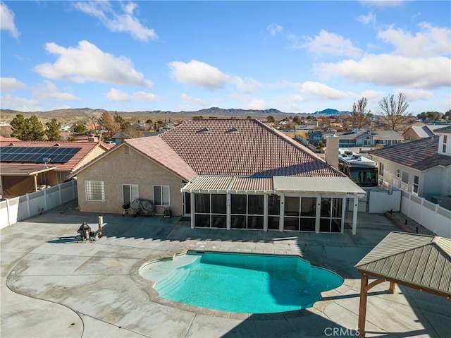 view of pool featuring a mountain view, a sunroom, and a patio