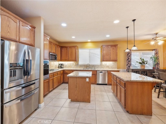 kitchen with a kitchen island, appliances with stainless steel finishes, decorative light fixtures, sink, and decorative backsplash