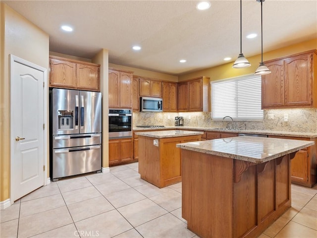 kitchen featuring pendant lighting, sink, appliances with stainless steel finishes, tasteful backsplash, and a kitchen island