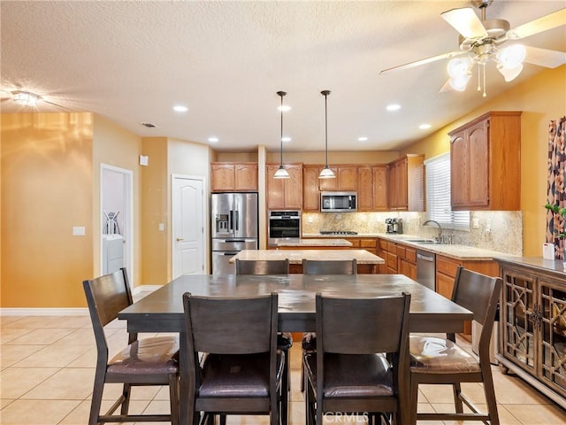 kitchen featuring sink, light tile patterned floors, backsplash, stainless steel appliances, and independent washer and dryer