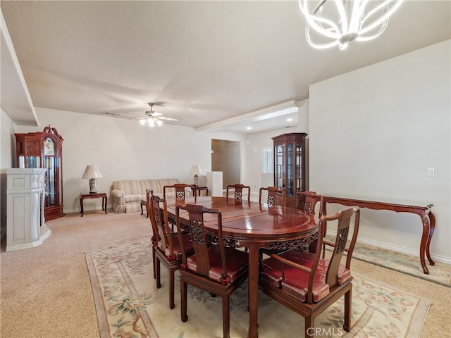 dining area with ceiling fan with notable chandelier and light colored carpet