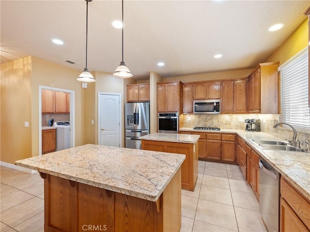 kitchen with sink, a center island, light tile patterned floors, pendant lighting, and stainless steel appliances