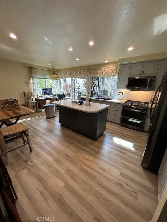 kitchen featuring stainless steel appliances, gray cabinets, light hardwood / wood-style floors, and a kitchen island