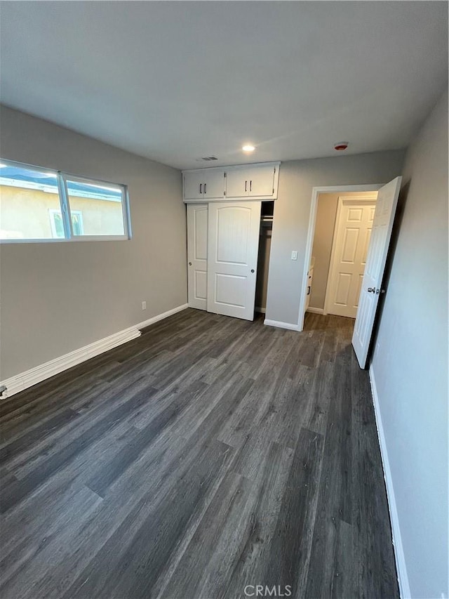 unfurnished bedroom with dark hardwood / wood-style floors and a closet