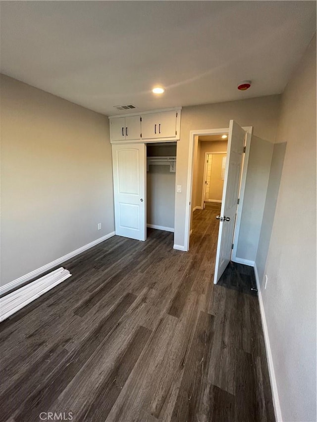 unfurnished bedroom with dark wood-type flooring and a closet