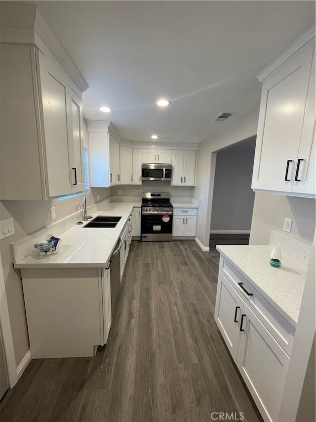 kitchen with white cabinetry, appliances with stainless steel finishes, light stone countertops, and sink