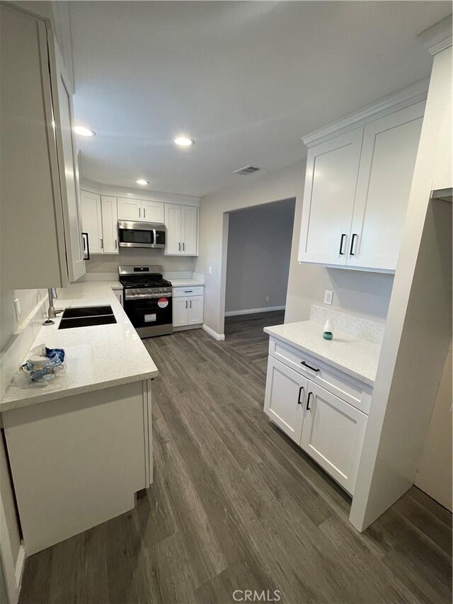 kitchen featuring dark wood-type flooring, sink, stainless steel appliances, light stone countertops, and white cabinets