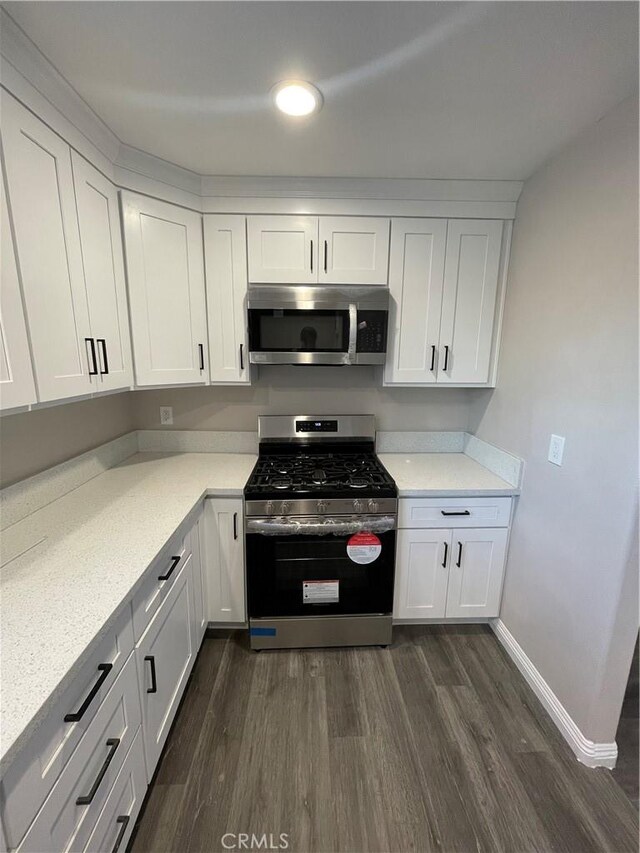 kitchen featuring white cabinetry, appliances with stainless steel finishes, dark hardwood / wood-style flooring, and light stone countertops