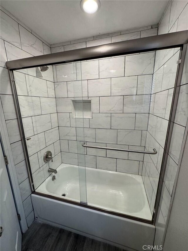 bathroom with wood-type flooring and enclosed tub / shower combo