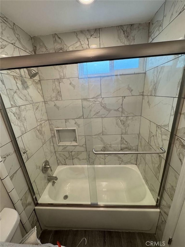 bathroom featuring enclosed tub / shower combo and toilet