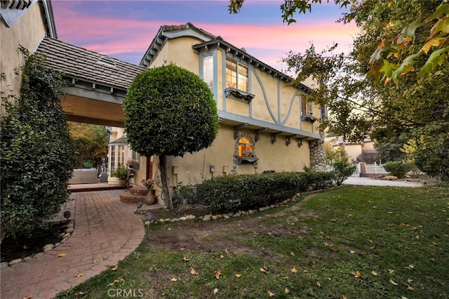 property exterior at dusk with a yard and a patio area