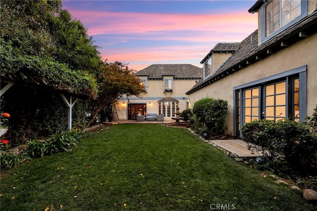 yard at dusk with a patio and french doors