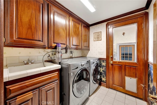 washroom with light tile patterned flooring, sink, cabinets, ornamental molding, and washer and clothes dryer