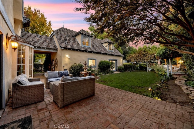 patio terrace at dusk featuring outdoor lounge area and a yard