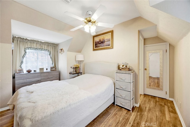 bedroom with hardwood / wood-style flooring, vaulted ceiling, and ceiling fan