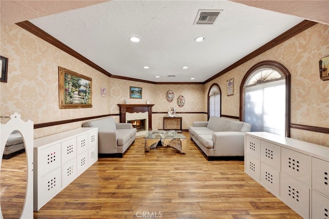 living room featuring ornamental molding, a textured ceiling, and light wood-type flooring