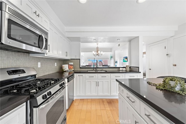 kitchen with appliances with stainless steel finishes, sink, white cabinets, and light hardwood / wood-style flooring