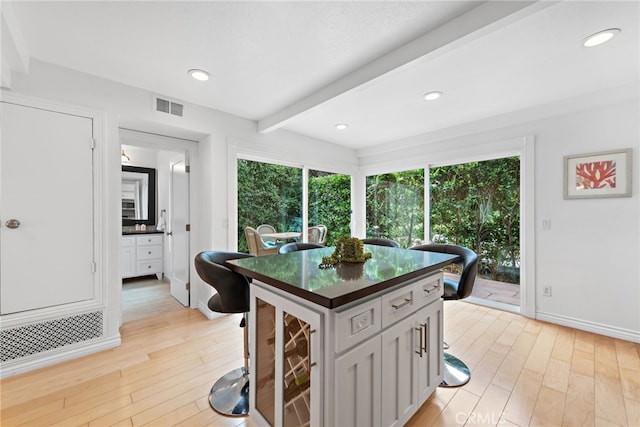 kitchen with gray cabinetry, a wealth of natural light, beam ceiling, and light hardwood / wood-style flooring