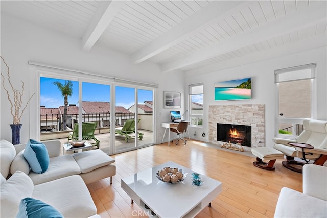 living room with a fireplace, beam ceiling, plenty of natural light, and light hardwood / wood-style floors