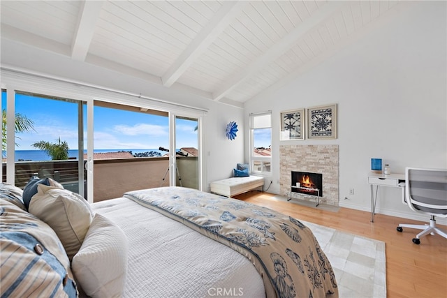 bedroom with hardwood / wood-style floors, a stone fireplace, wooden ceiling, and a water view