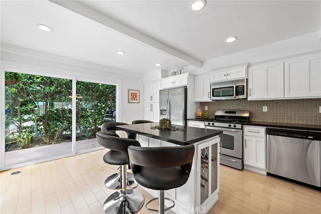 kitchen featuring beamed ceiling, stainless steel appliances, and white cabinets