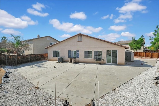 rear view of house with a storage unit and a patio area