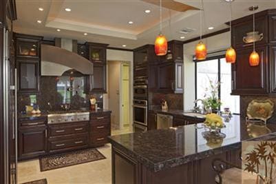 kitchen featuring appliances with stainless steel finishes, decorative light fixtures, wall chimney range hood, and a tray ceiling