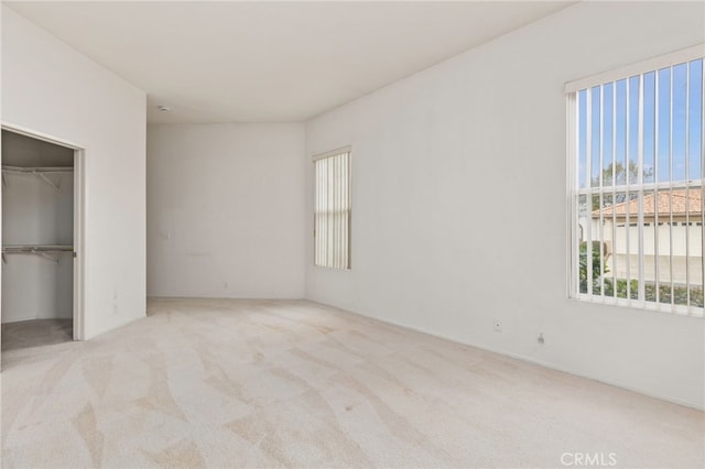 unfurnished bedroom with light carpet and a closet